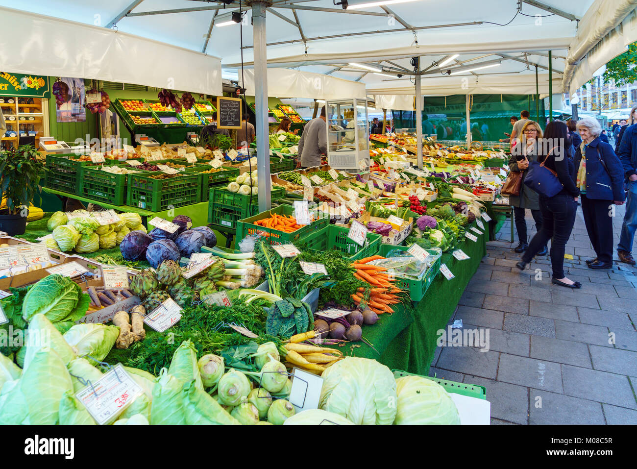Munich, Allemagne - 14 octobre 2017 : les touristes acheter différentes sortes de légumes sur le comptoir du marché Viktualienmarkt Banque D'Images