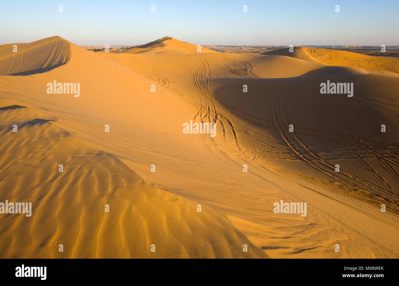 Dunes de sable avec des sentiers pendant le coucher du soleil dans le désert aux Emirats Arabes Unis. Banque D'Images