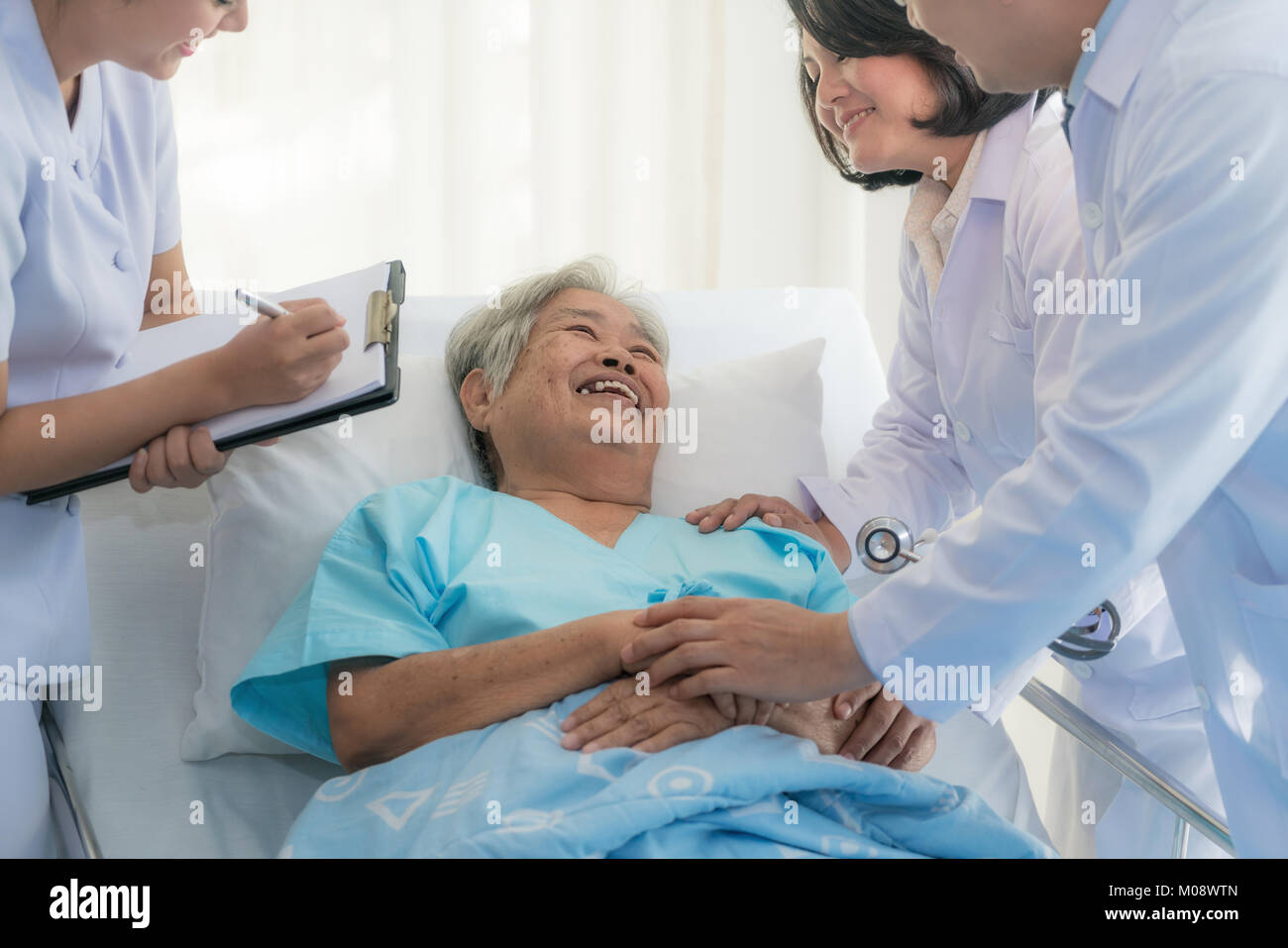 Asian medical équipe de médecins d'examiner et de parler aux personnes âgées Asie femme patient, les soins de personnes de prendre note sur le presse-papiers à l'hôpital. Banque D'Images