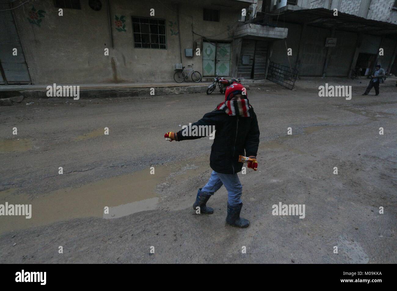 Mesraba, la Syrie. 18 janvier, 2018. Un garçon vu jouant dans la rue au cours de la pluie dans un village en dehors de damas.Malgré le conflit en cours en Syrie, dans la vie des pièces détenues par le gouvernement de Damas et autour de la capitale, porte toujours sur relativement pacifiquement. Damas, la capitale de la Syrie, est le plus souvent sous contrôle officiel par le gouvernement syrien du président Bachar al-Assad. Credit : Muhmmad Al-Najjar/SOPA/ZUMA/Alamy Fil Live News Banque D'Images