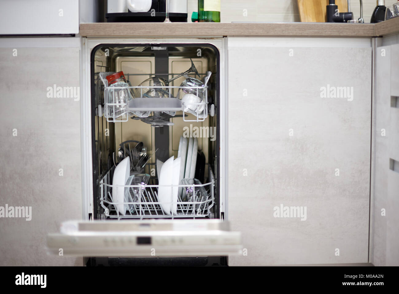 Lave-vaisselle machine en charge d'une cuisine moderne avec des assiettes et des verres Banque D'Images