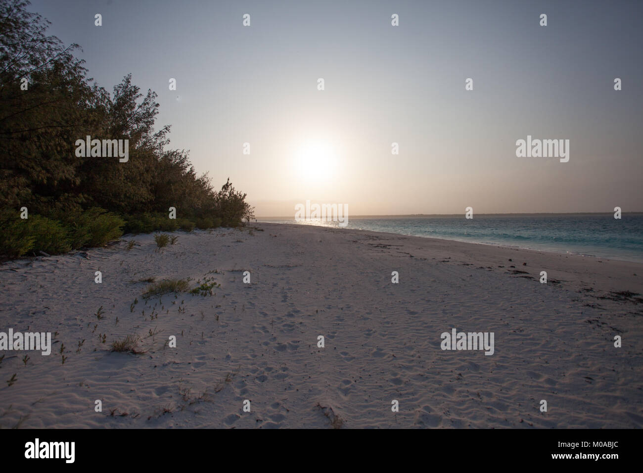Le lever du soleil fournit à cette lueur tôt le matin sur la plage sur une île tropicale Banque D'Images
