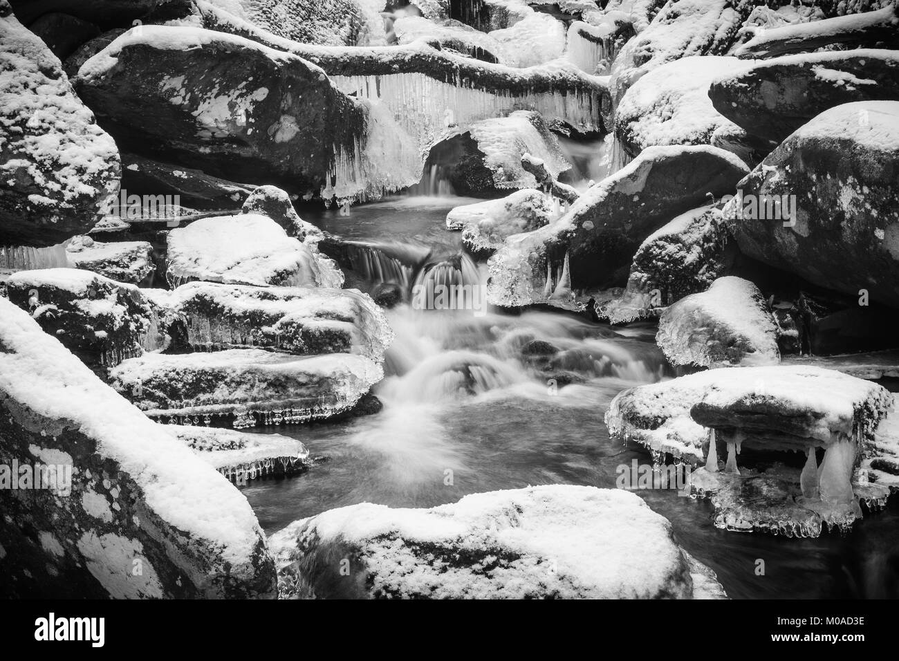 Froide journée d'hiver. L'écoulement de l'eau brouillée avec cascade, rochers dans un ruisseau ou un cours d'eau. Banque D'Images