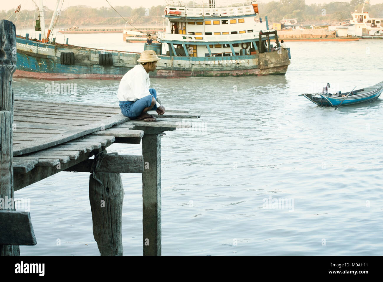 Birmese homme assis sur un quai sur le fleuve Yangon. 22 février 2014 - Yangon, Myanmar Banque D'Images