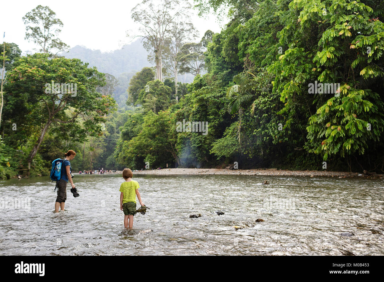 Mère et fils crossing river pieds nus dans le parc national de Gunung Leuser de Tangkahan, Sumatra, Indonésie Banque D'Images