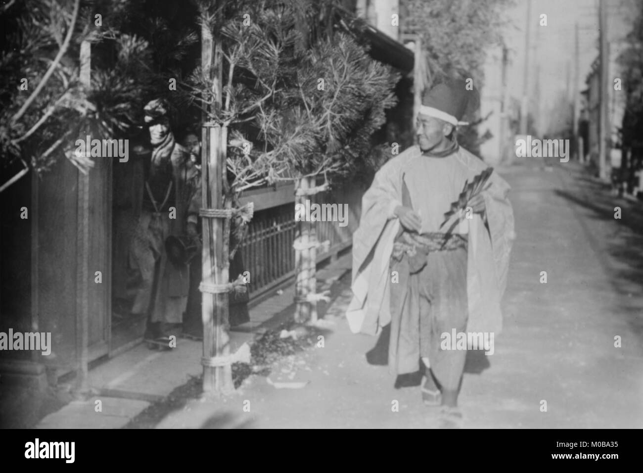 Salutation du nouvel an au Japon ; homme japonais en robe autochtone marche dans une petite rue donnant des salutations du nouvel an Banque D'Images