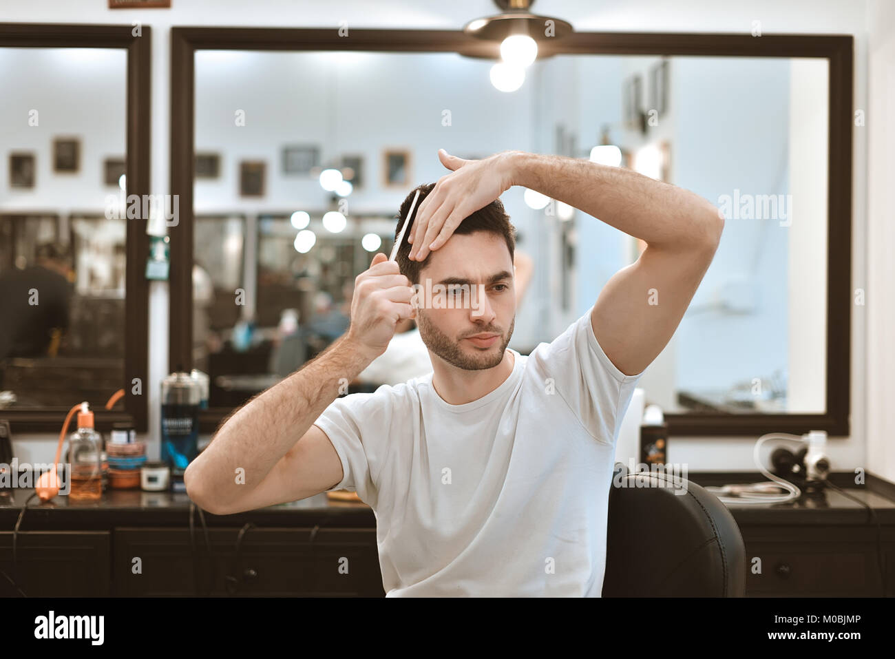 Processus de travail moderne dans un salon de barbier. Beau coiffure au service client, la mise en forme pour les clients masculins à l'aide d'un sèche-cheveux. Vue de côté portrait d'ATTRA Banque D'Images