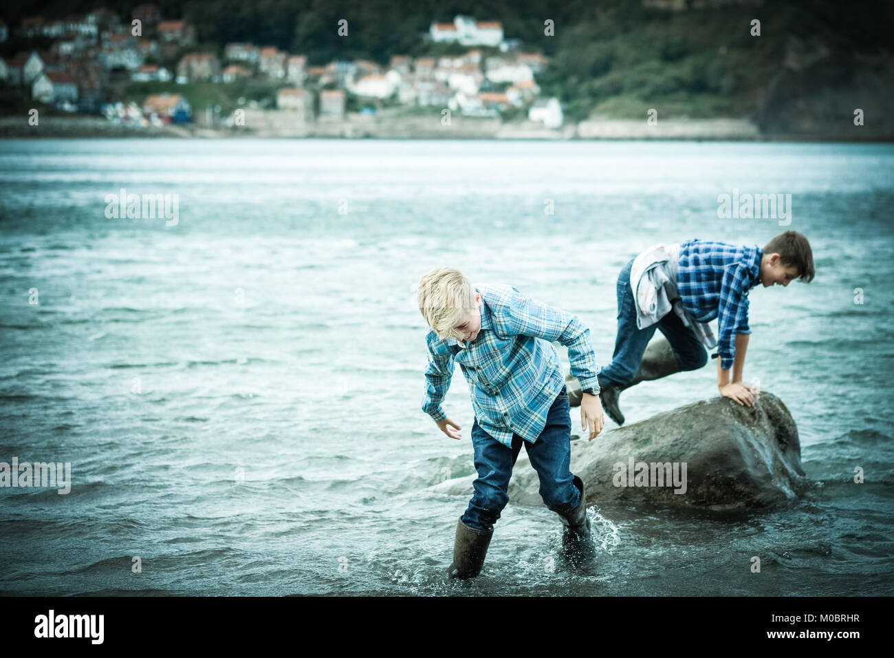 Deux frères, les garçons 12 et 10 ans, dans la mer, en crabe, jouer, à Runswick Bay, Yorkshire, UK Banque D'Images