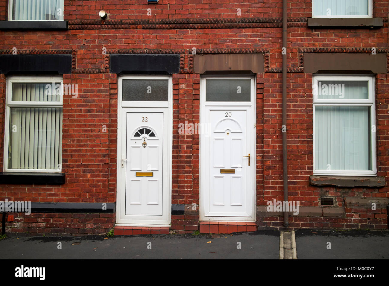 Les portes en PVC blanc moderne sur deux chambres mitoyennes de style victorien en briques rouges ward street St Helens merseyside uk Banque D'Images
