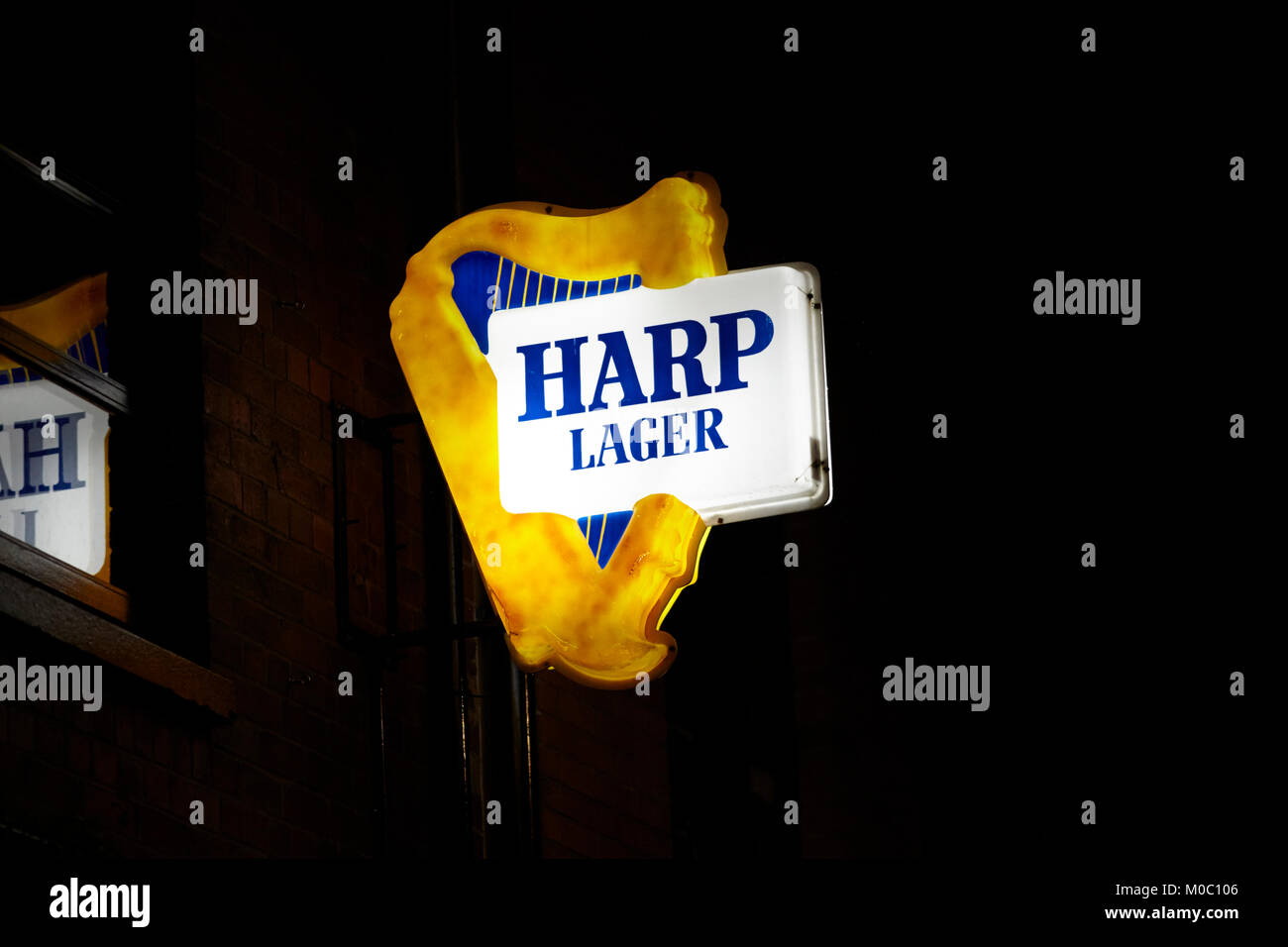 Harpe éclairé plus d'un signe de la lager pub sur une sombre nuit humide de l'Irlande du Nord à Belfast, Royaume-Uni Banque D'Images
