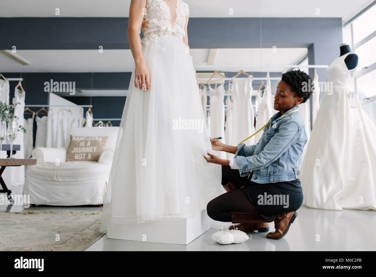 Femme africaine d'effectuer le réglage à robe de designer de mode en studio. Bride standing dans sa robe avec robe femme designer décisions fina Banque D'Images