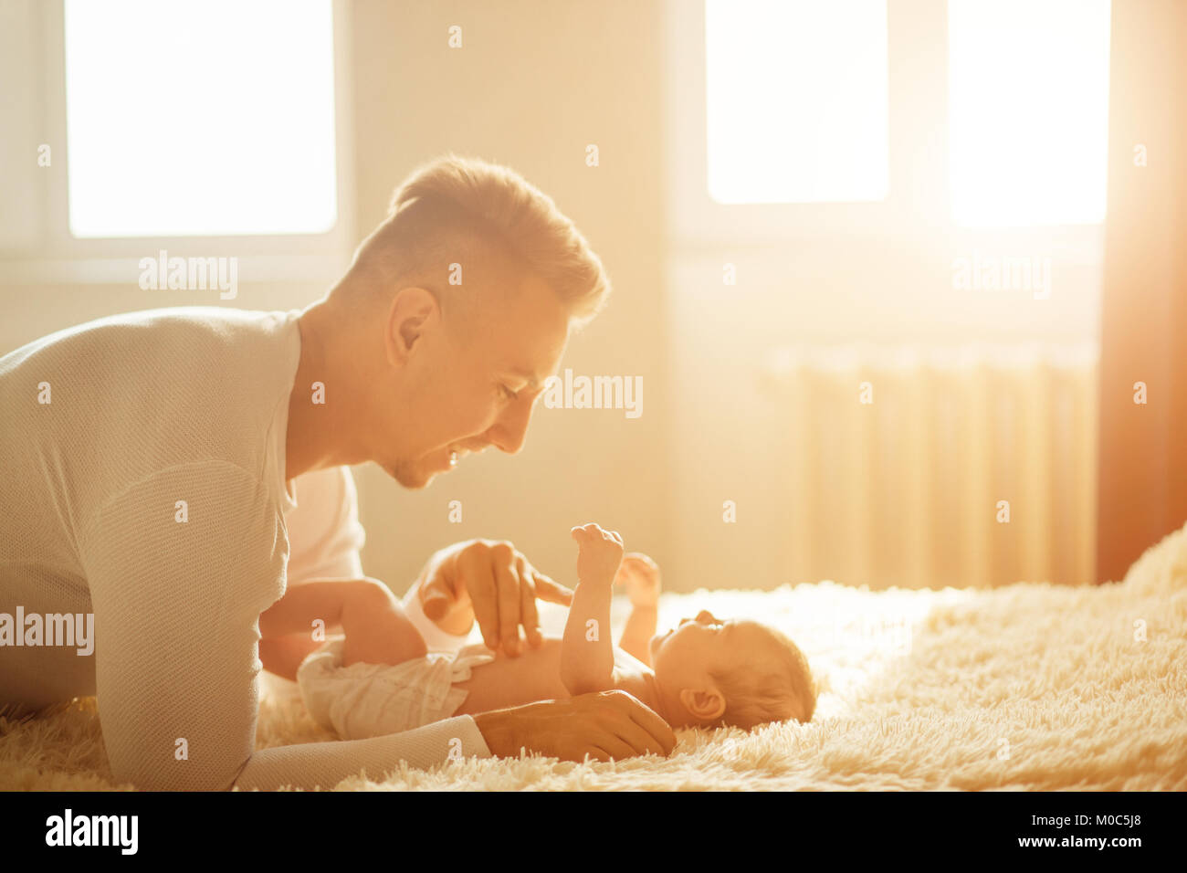 Père couché sur lit et tient son bébé Banque D'Images