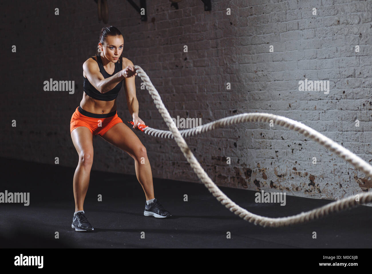 Athletic woman doing battle rope exercices au gymnase Banque D'Images