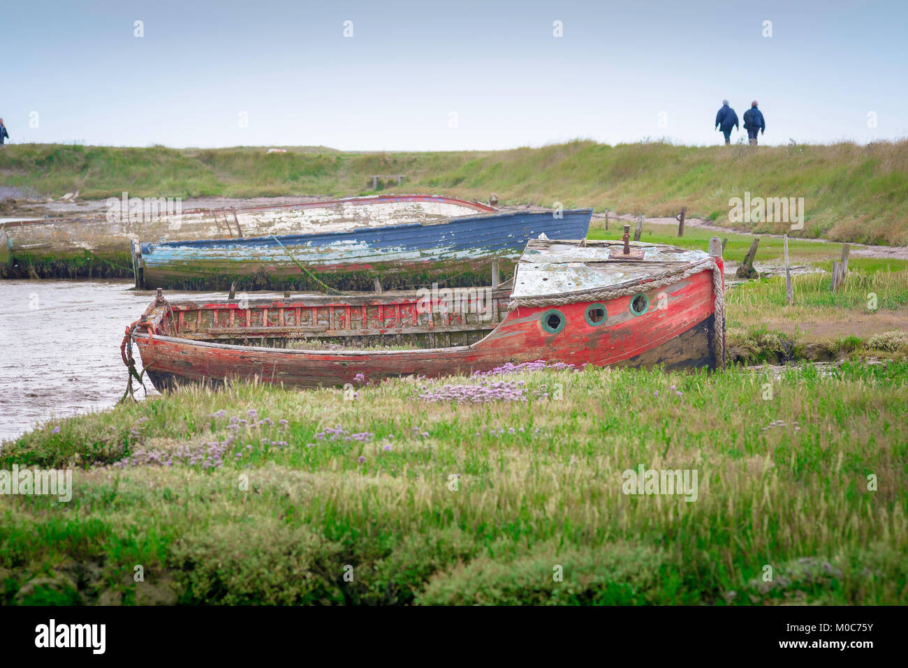 Côte d'Orford Suffolk, vue le long des rives de la rivière ADLE à Orford avec un couple marchant sur le Suffolk Coast Path in the loin, Suffolk, Royaume-Uni Banque D'Images