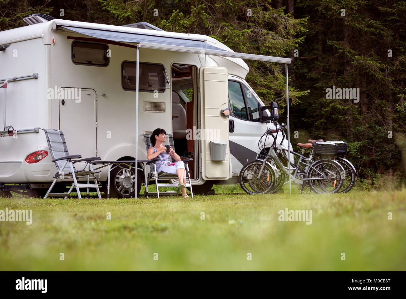 Femme se tient debout avec une tasse de café près de la camionnette. Location caravane Vacances. Vacances famille vacances, voyages voyage en camping-car Banque D'Images