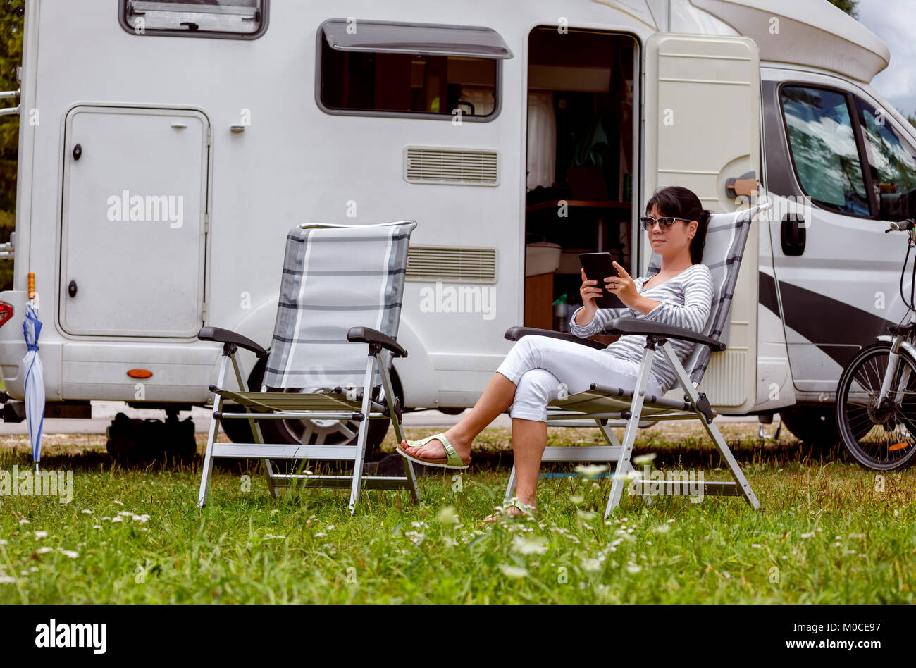Femme regardant la tablette à côté du camping . Location caravane Vacances. Vacances famille vacances, voyages voyage en camping-car. Informations de connexion wi-fi Banque D'Images