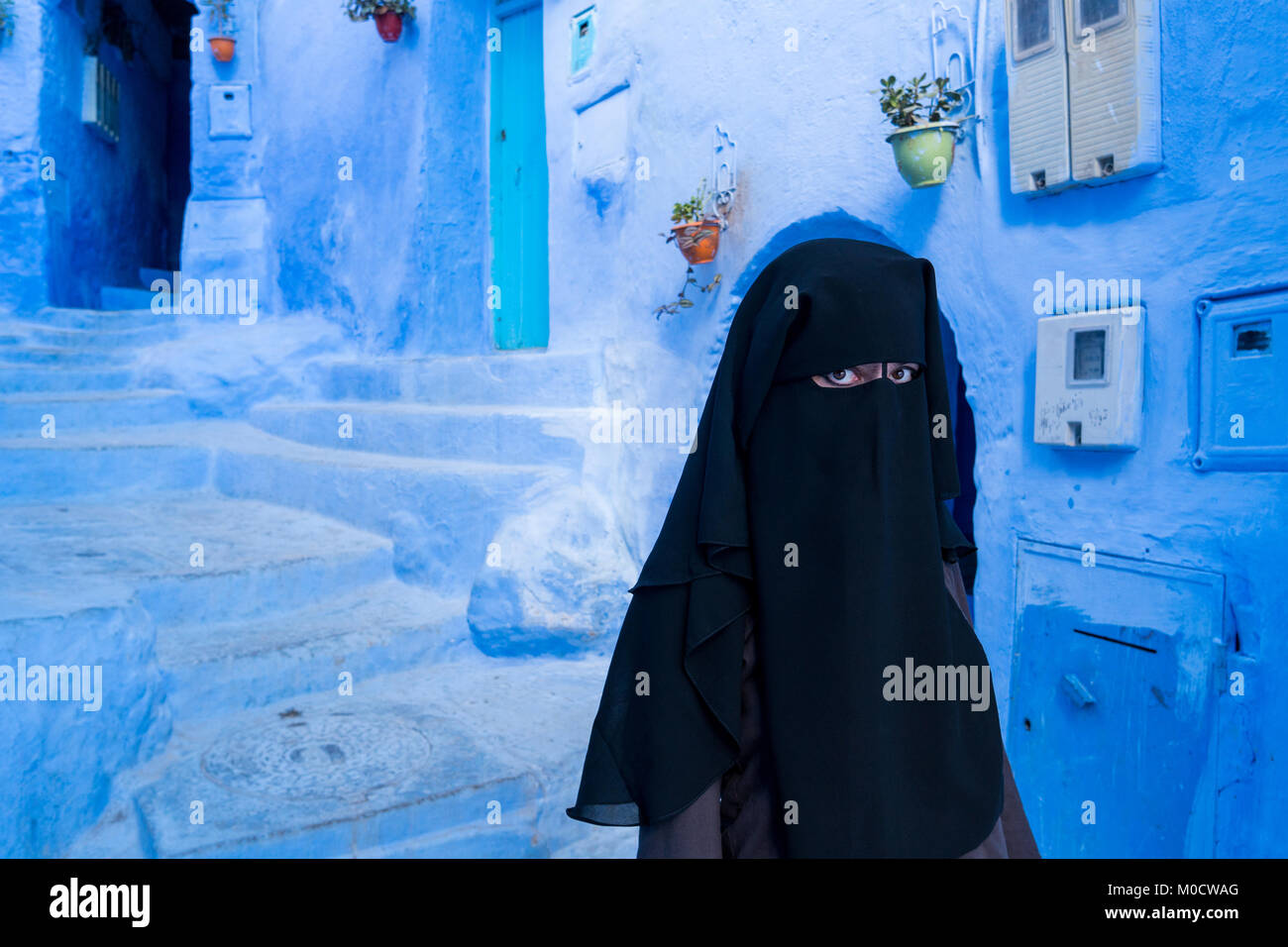 Femme musulmane à visage couvert de niqab noir à Chefchaouen, la ville bleue, au Maroc Banque D'Images