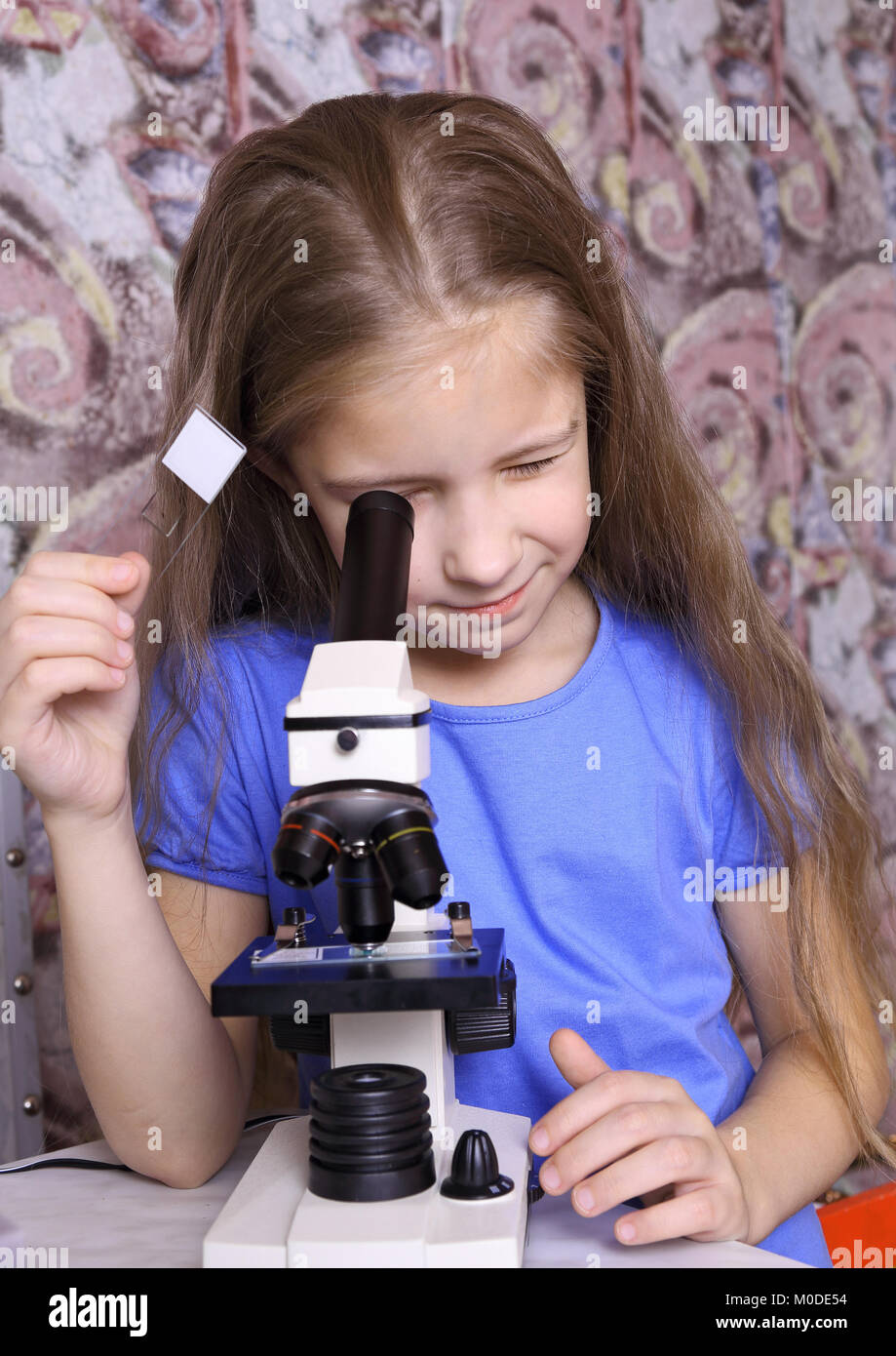 Fille avec intérêt à la recherche à l'aide d'un microscope Banque D'Images