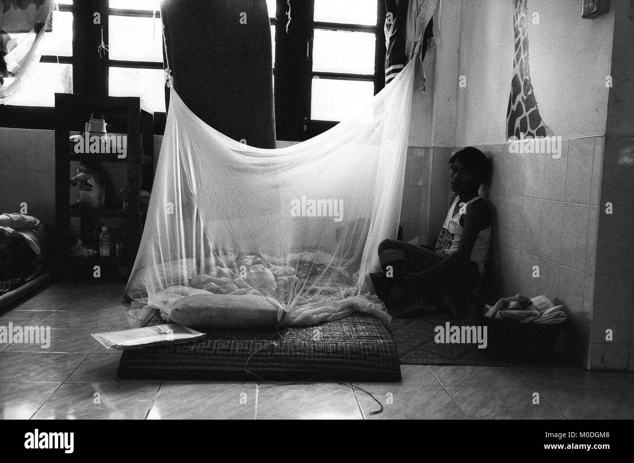 Un père veille sur son enfant malade dans le service de pédiatrie à la clinique Mae Tao sur la frontière thaïlando-birmane. Environ 300 personnes par jour reçoivent des soins gratuits à la clinique, la plupart étant des travailleurs migrants et réfugiés qui ont franchi la frontière de la Birmanie (Myanmar) pour échapper à la pauvreté désespérée et la persécution du régime militaire. Les soins de santé sont tous mais inexistante en Birmanie, où moins de 2  % du PIB est consacré à la santé et l'éducation combinées. Banque D'Images