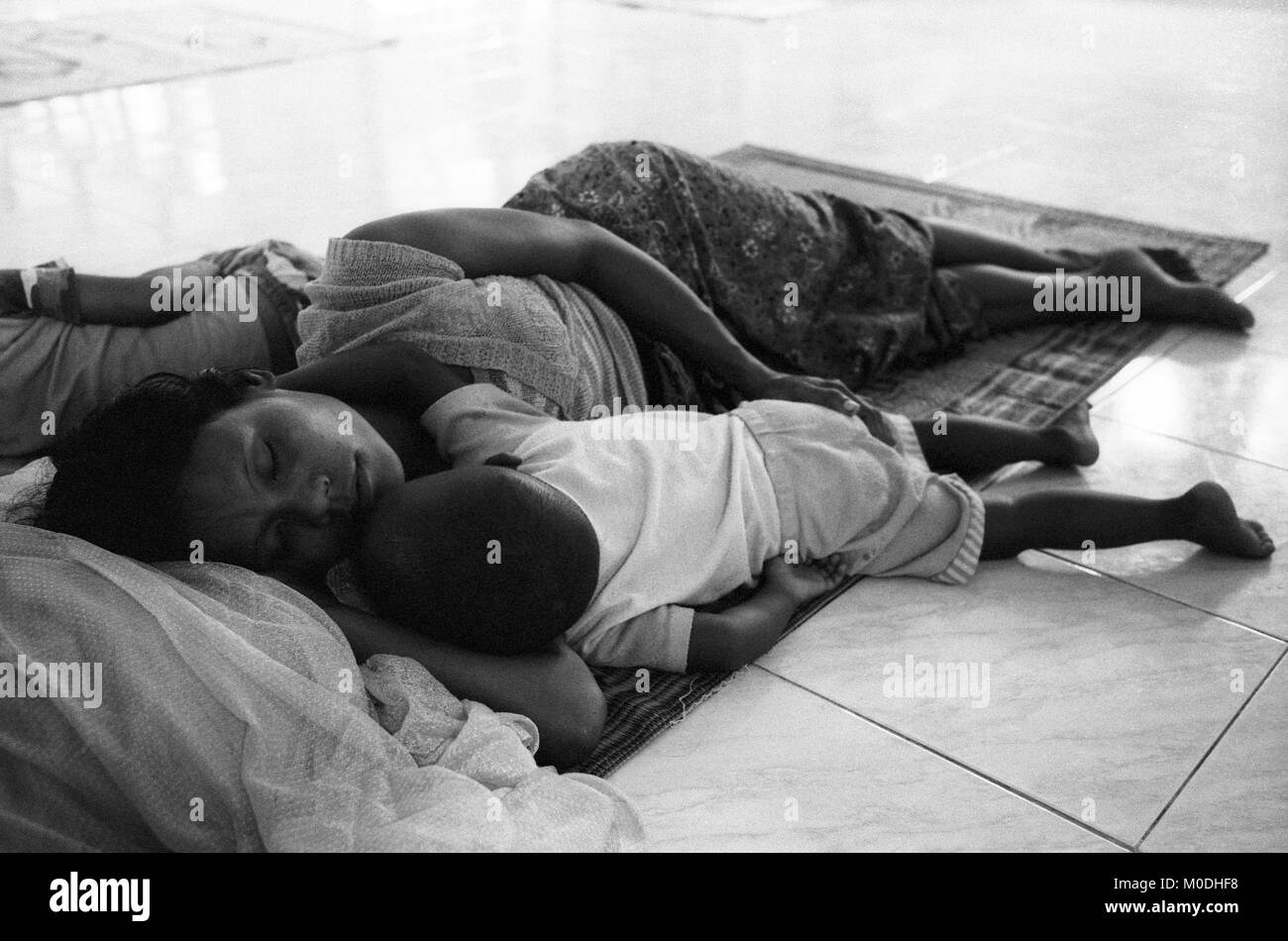 Une mère dort à côté d'elle les enfants malades dans le service de pédiatrie à la clinique Mae Tao sur la frontière thaïlando-birmane. Environ 300 personnes par jour reçoivent des soins gratuits à la clinique, la plupart étant des travailleurs migrants et réfugiés qui ont franchi la frontière de la Birmanie (Myanmar) pour échapper à la pauvreté désespérée et la persécution du régime militaire. Les soins de santé sont tous mais inexistante en Birmanie, où moins de 2  % du PIB est consacré à la santé et l'éducation combinées. Banque D'Images