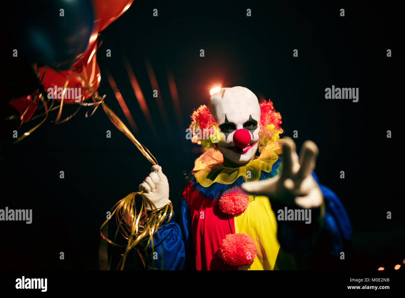 Photo de clown souriant avec des boules dans les mains la nuit Banque D'Images