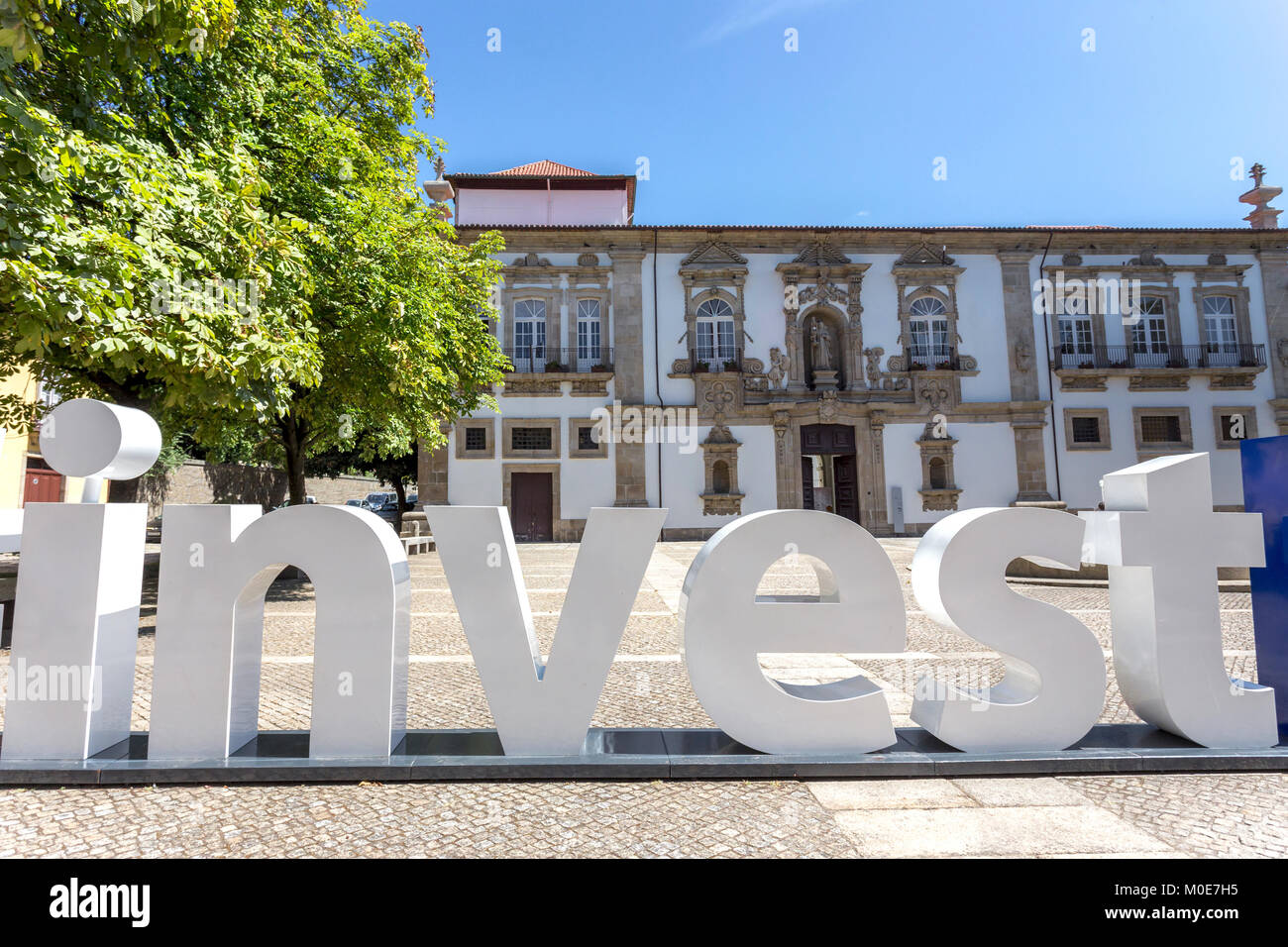 Mot Investir créé par grandes lettres en plastique en face de l'architecture traditionnelle Banque D'Images