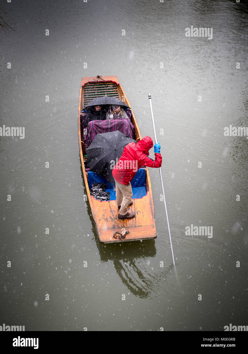 Barque d'hiver - Touristes trainent sous des couvertures et des parasols car ils prennent un punt sur la rivière Cam pendant un temps neigeux. Banque D'Images