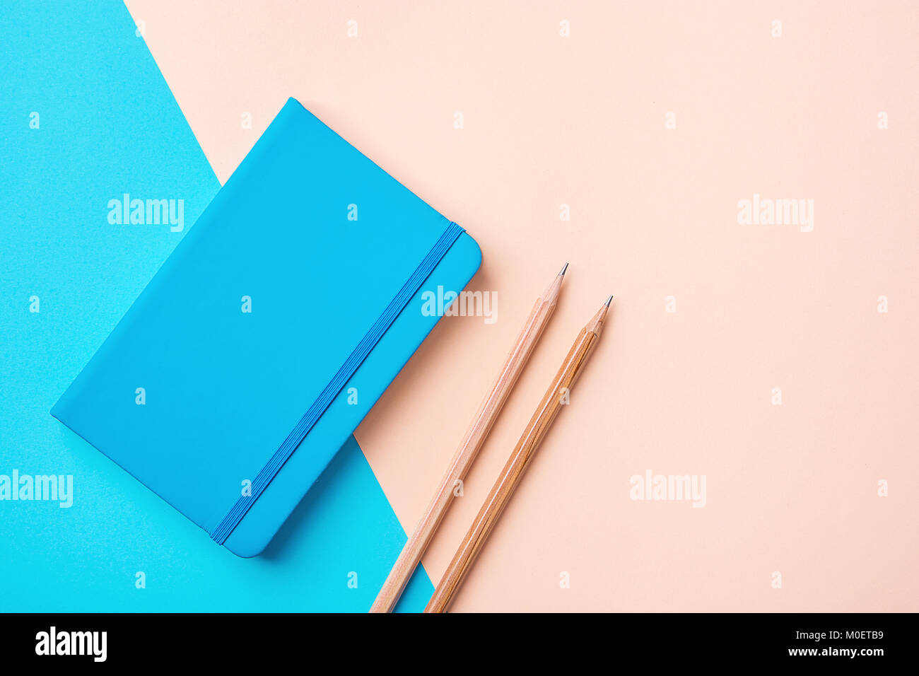 Le bloc-notes d'écriture crayons bois bleu contraste sur un fond de couleur pastel rose pêche combinaison. La planification de l'Organisation systématique de l'éducation entreprise Concept Banque D'Images