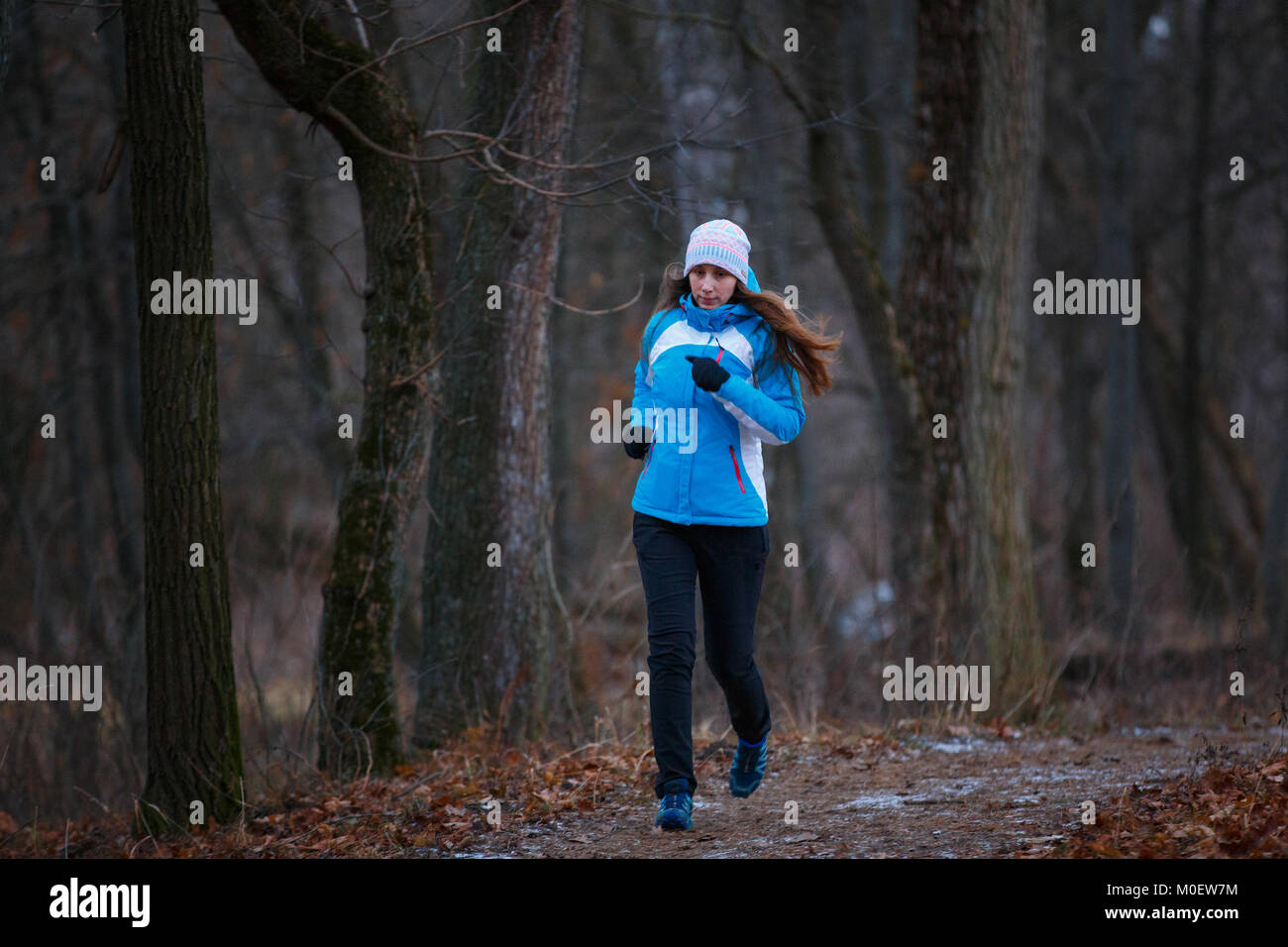 Activité de plein air en hiver image conceptuelle. Young woman running in park par temps froid Banque D'Images