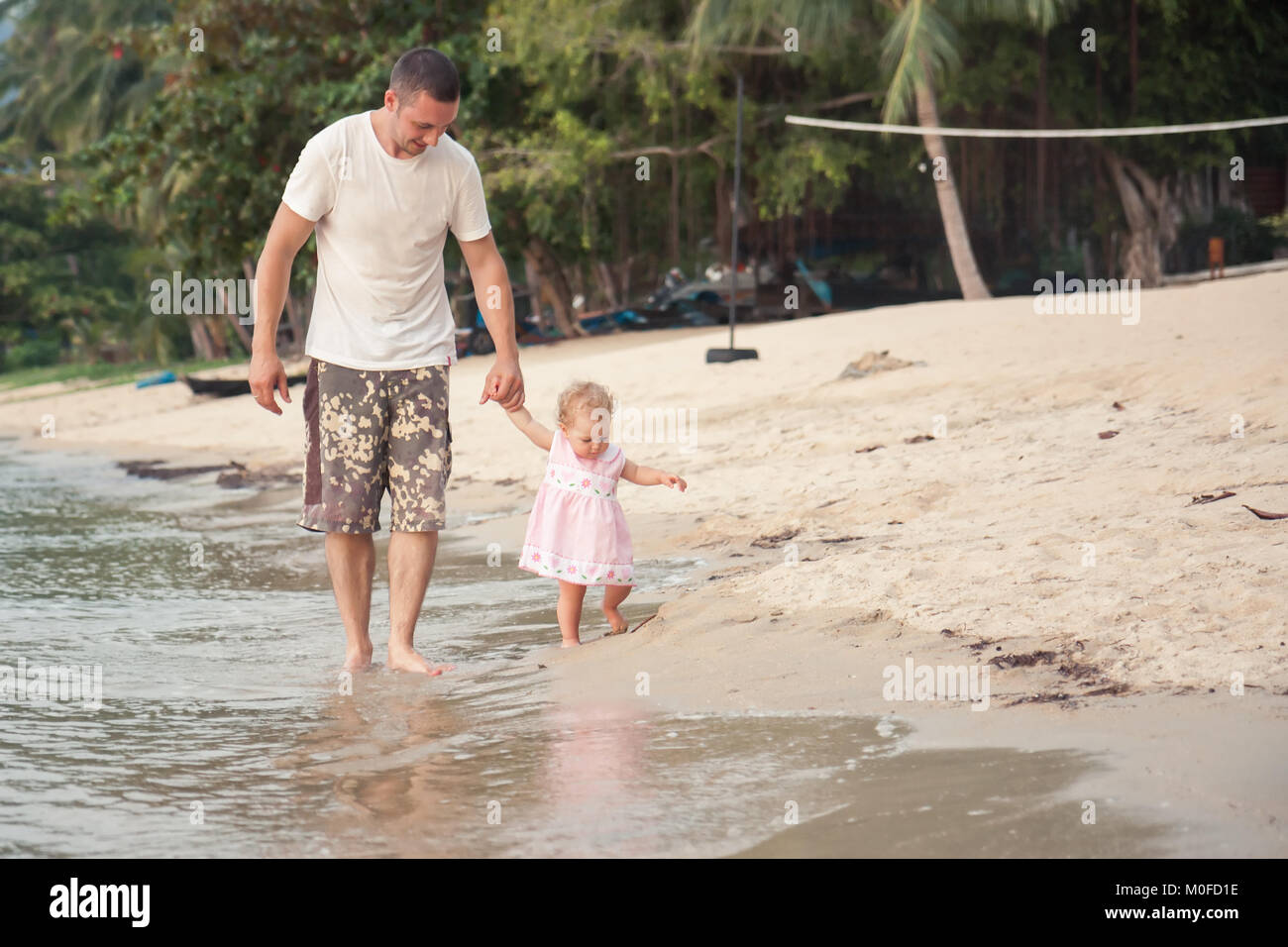 Heureux père et petite fille à marcher ensemble avec holding hands on beach Banque D'Images
