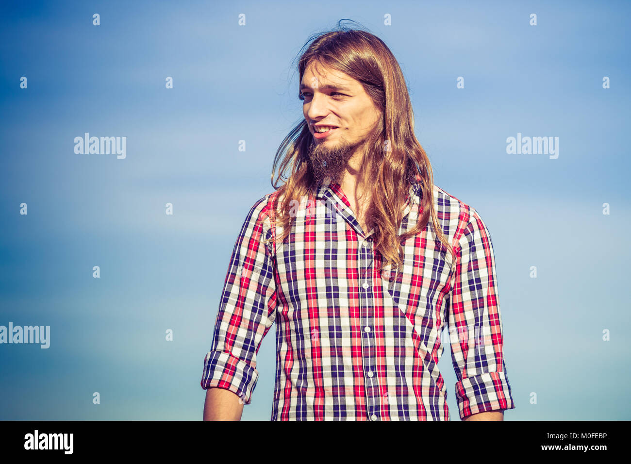 Homme cheveux longs portant chemise à carreaux relaxant à l'extérieur de  jour de vent contre le ciel bleu Photo Stock - Alamy