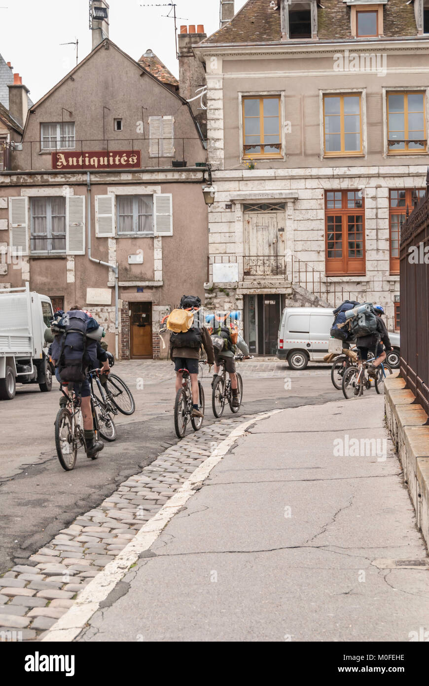 Les garçons d'âge scolaire français sur leurs bicyclettes avec des sacs à dos équitation dans une rue de Chartres Banque D'Images