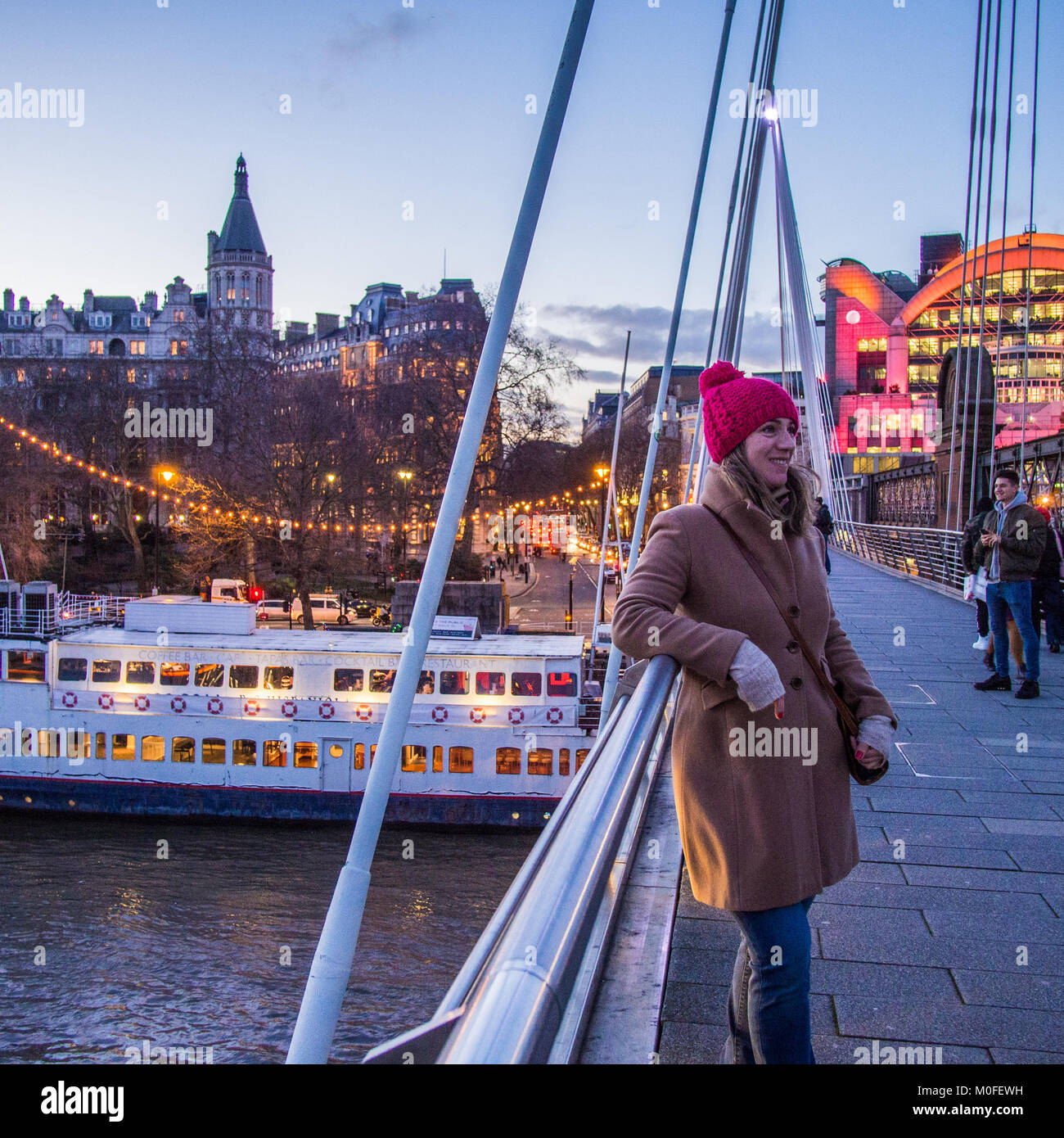 Dame posant pour une photo sur Golden Jubilee Bridge Londres. Hungerford pont de chemin de fer et la gare de Charing Cross sur la droite Banque D'Images