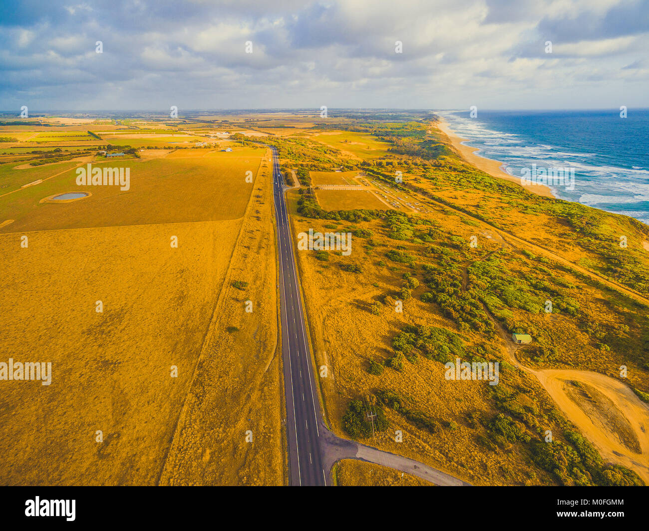 Tout droit chemin rural traversant les pâturages au coucher du soleil - vue aérienne. Melbourne, Victoria, Australie Banque D'Images
