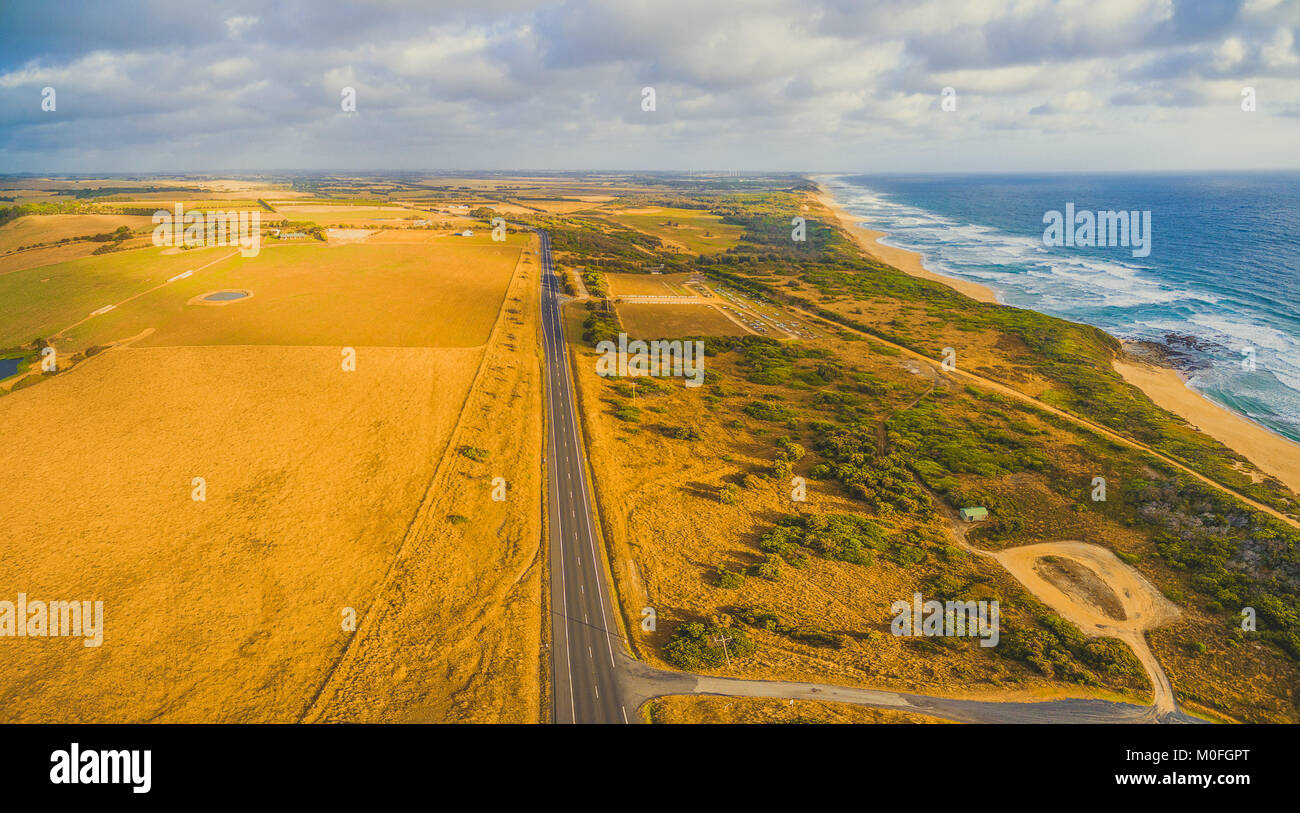 Route de campagne ouvre la voie à l'horizon parmi de beaux paysages australiens au coucher du soleil paysage - vue aérienne Banque D'Images
