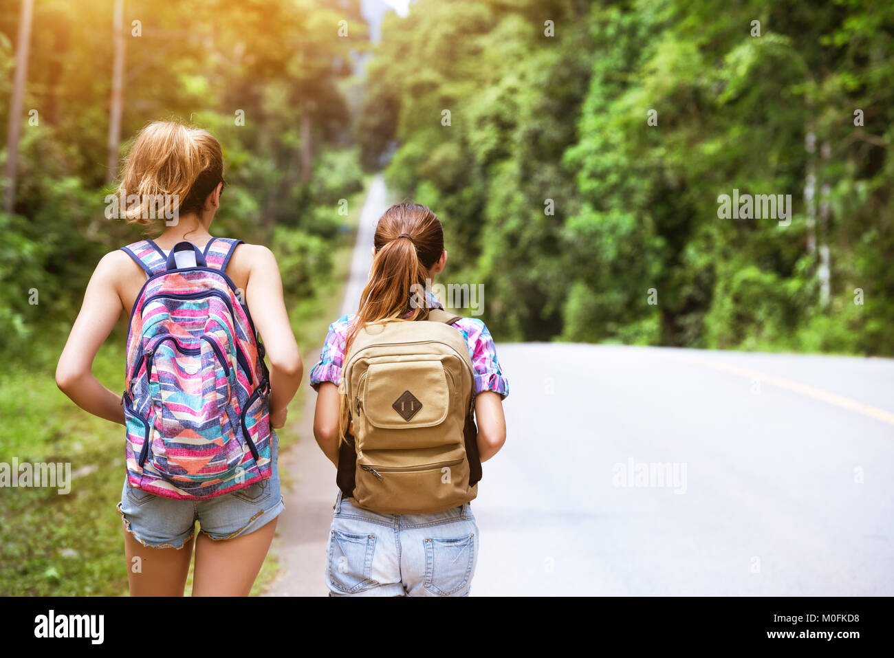 Deux jeunes filles avec des sacs vont par route droite Banque D'Images