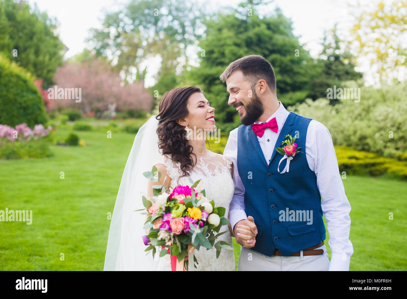L homme en chemise veste et cravate rose bow et buotonniere prendre le bras de sa femme en robe blanche avec voile mariage bouquet de pivoines a leur mariage d Photo Stock Alamy