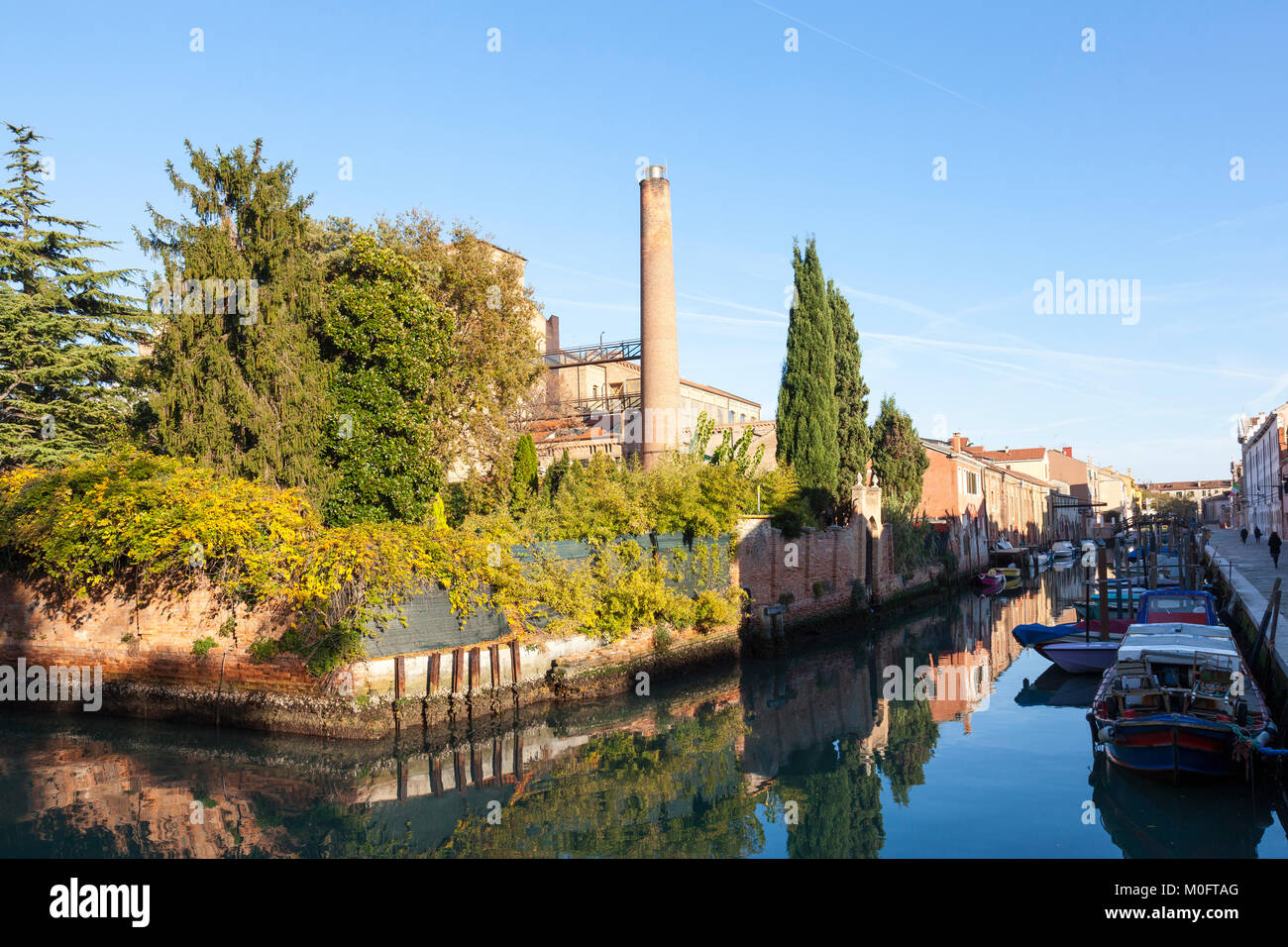 Cadre paisible Rio di San Biagio et canal latéral, l'île de Giudecca, à Venise, Italie au coucher du soleil avec des réflexions et de l'architecture industrielle convertie Banque D'Images