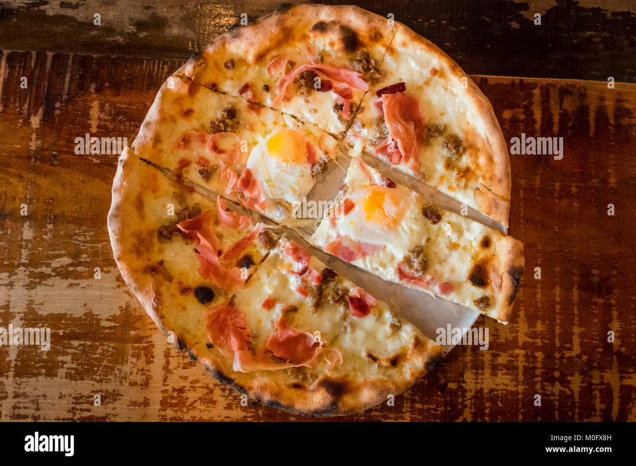 Un petit-déjeuner pizza, de fromage mozzarella, jambon cuit, saucisse et deux œufs Banque D'Images