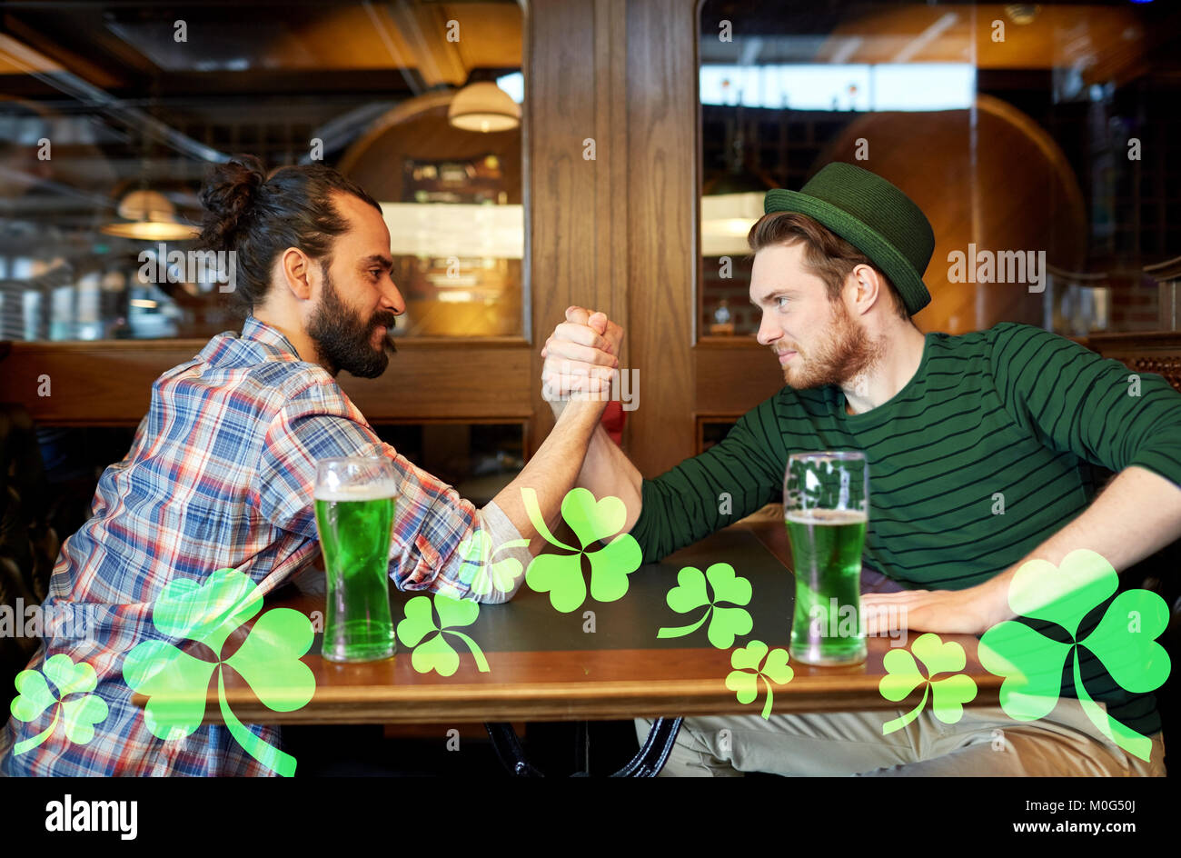 Les hommes de boire la bière verte et arm wrestling at pub Banque D'Images