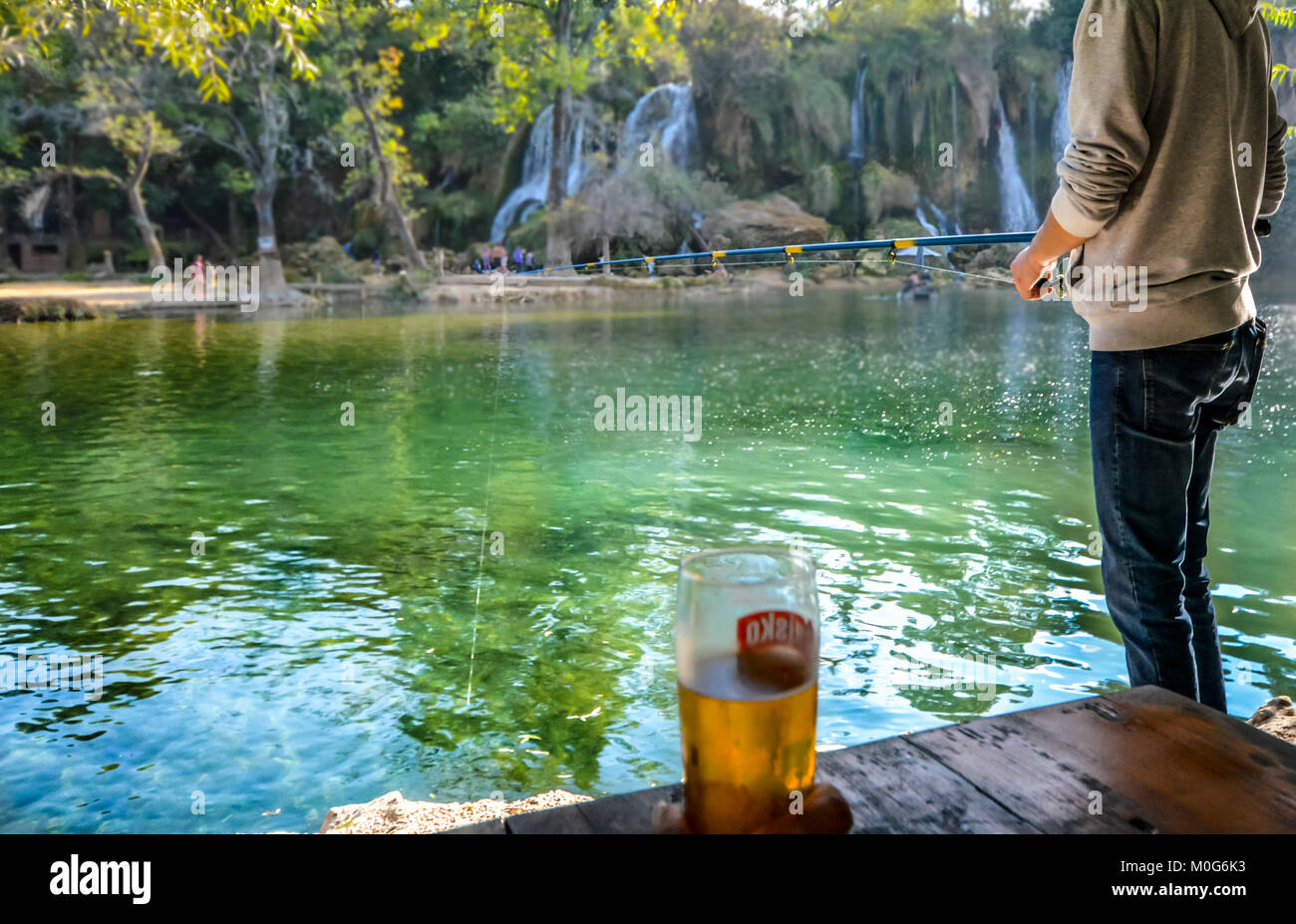 Un jeune homme avec canne et moulinet de pêche au lac à Kravica ou chutes de Kravice en Bosnie-Herzégovine sous le soleil d'après-midi d'automne Banque D'Images