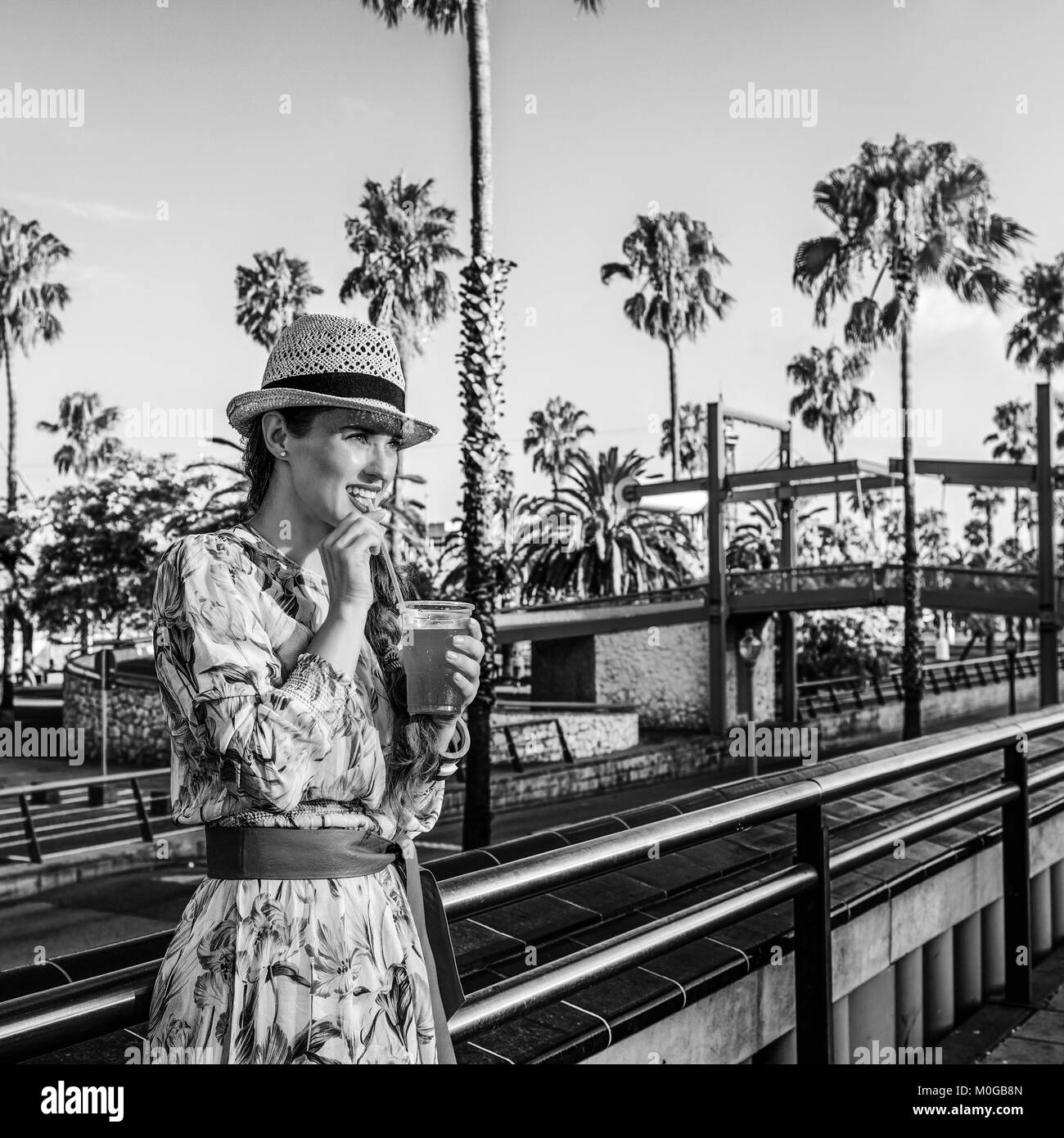 L'été à Barcelone coloré. jeune voyageur femme en robe et chapeau de paille sur le quai à Barcelone, Espagne boire boissons rouge vif Banque D'Images