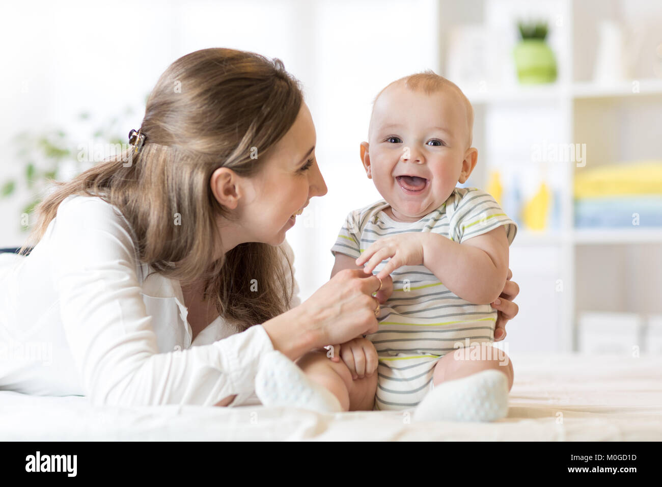 Maman et bébé garçon jouant dans une chambre ensoleillée. Heureuse mère et petit enfant kid de détente à la maison. Famille de s'amuser ensemble. Banque D'Images