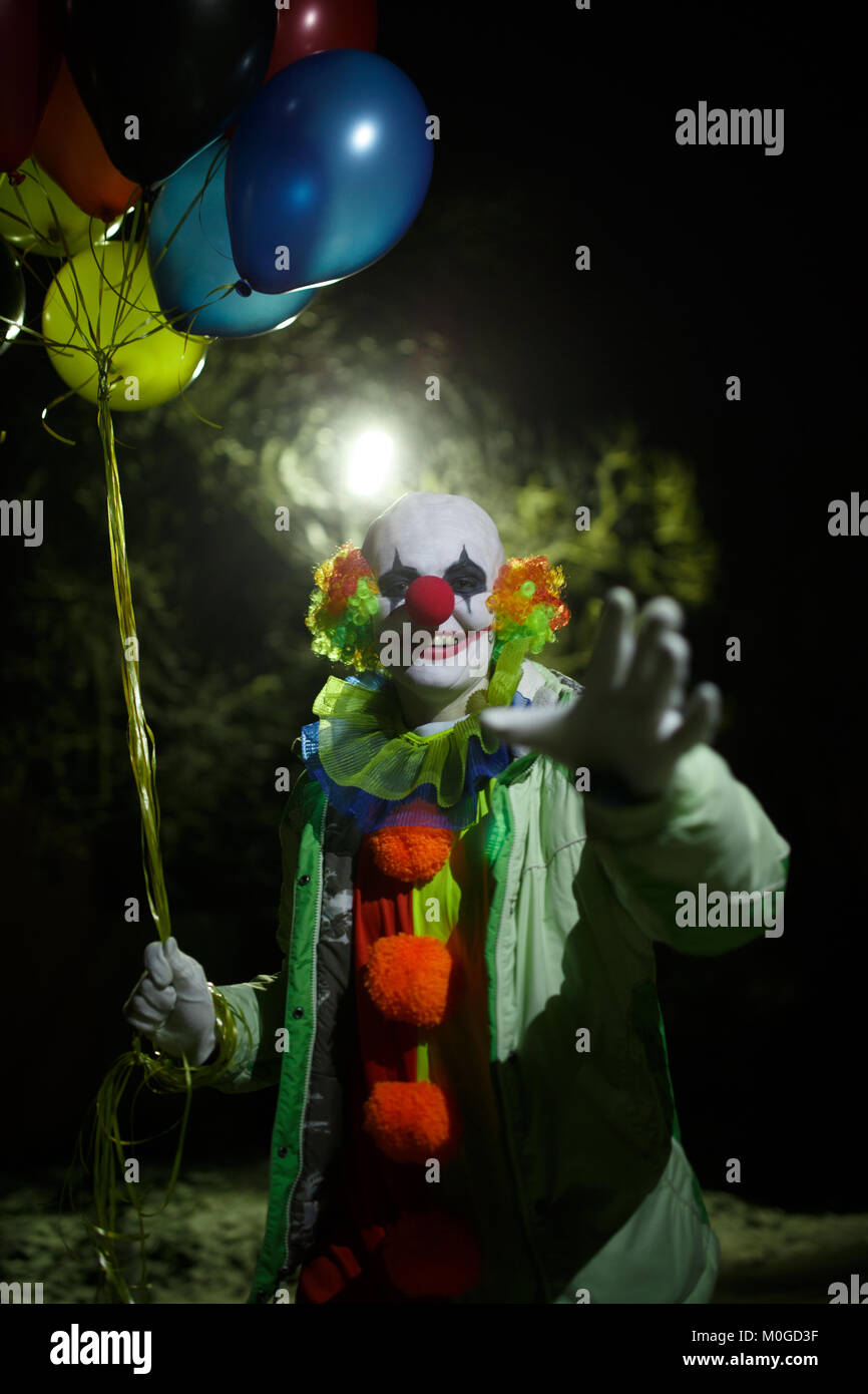 Photo de smiling clown aux ballons colorés dans la nuit Banque D'Images