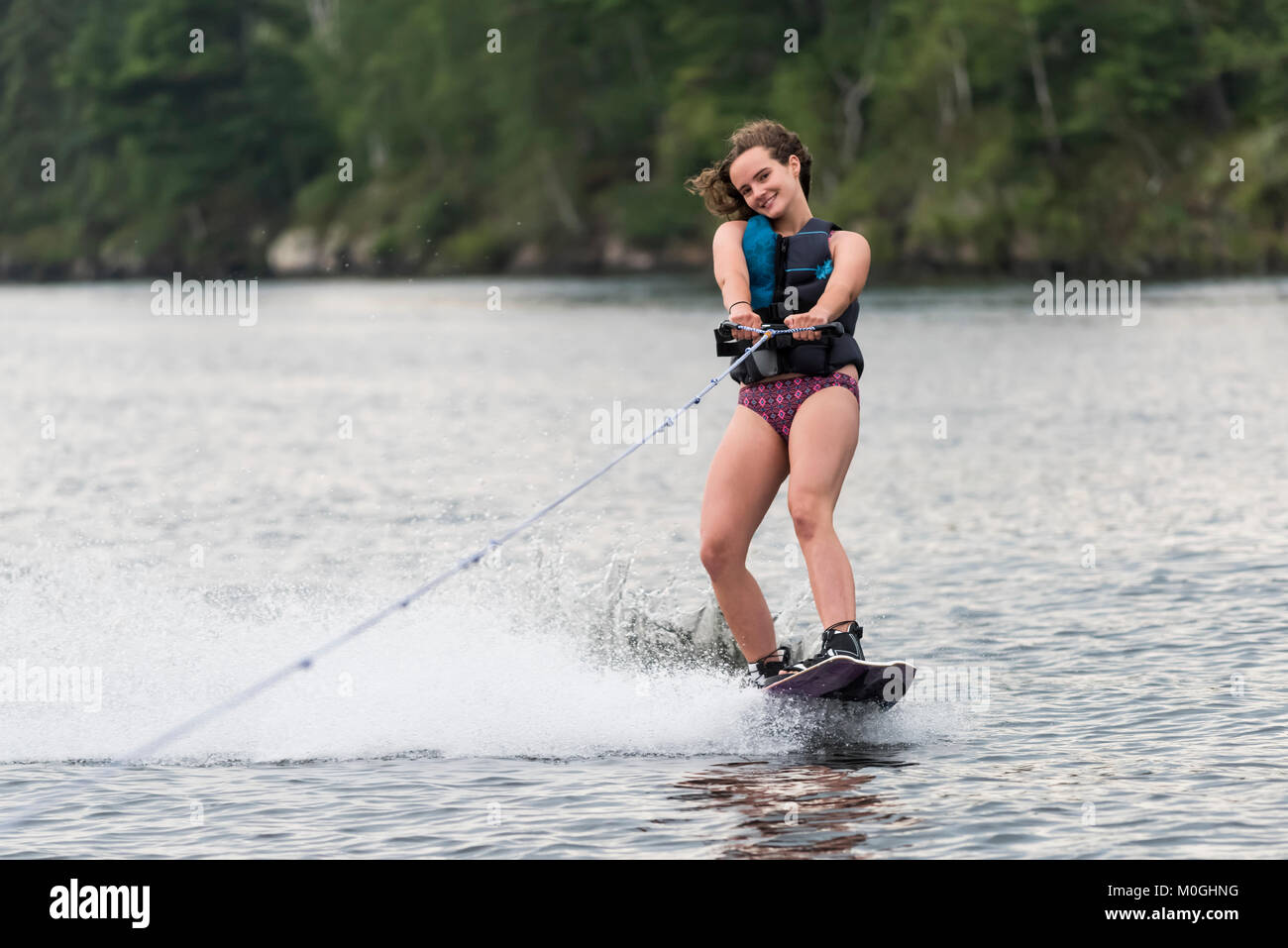 Une adolescente wakeboard derrière un bateau sur un lac, le lac des Bois, Ontario, Canada Banque D'Images