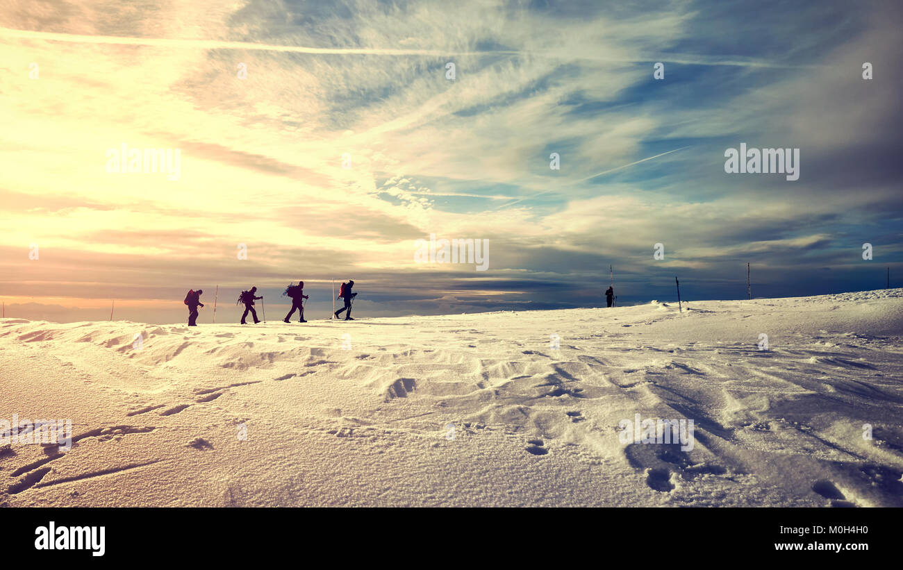 Paysage de montagne d'hiver avec des voyageurs silhouettes au coucher du soleil, aux teintes de couleur photo. Banque D'Images
