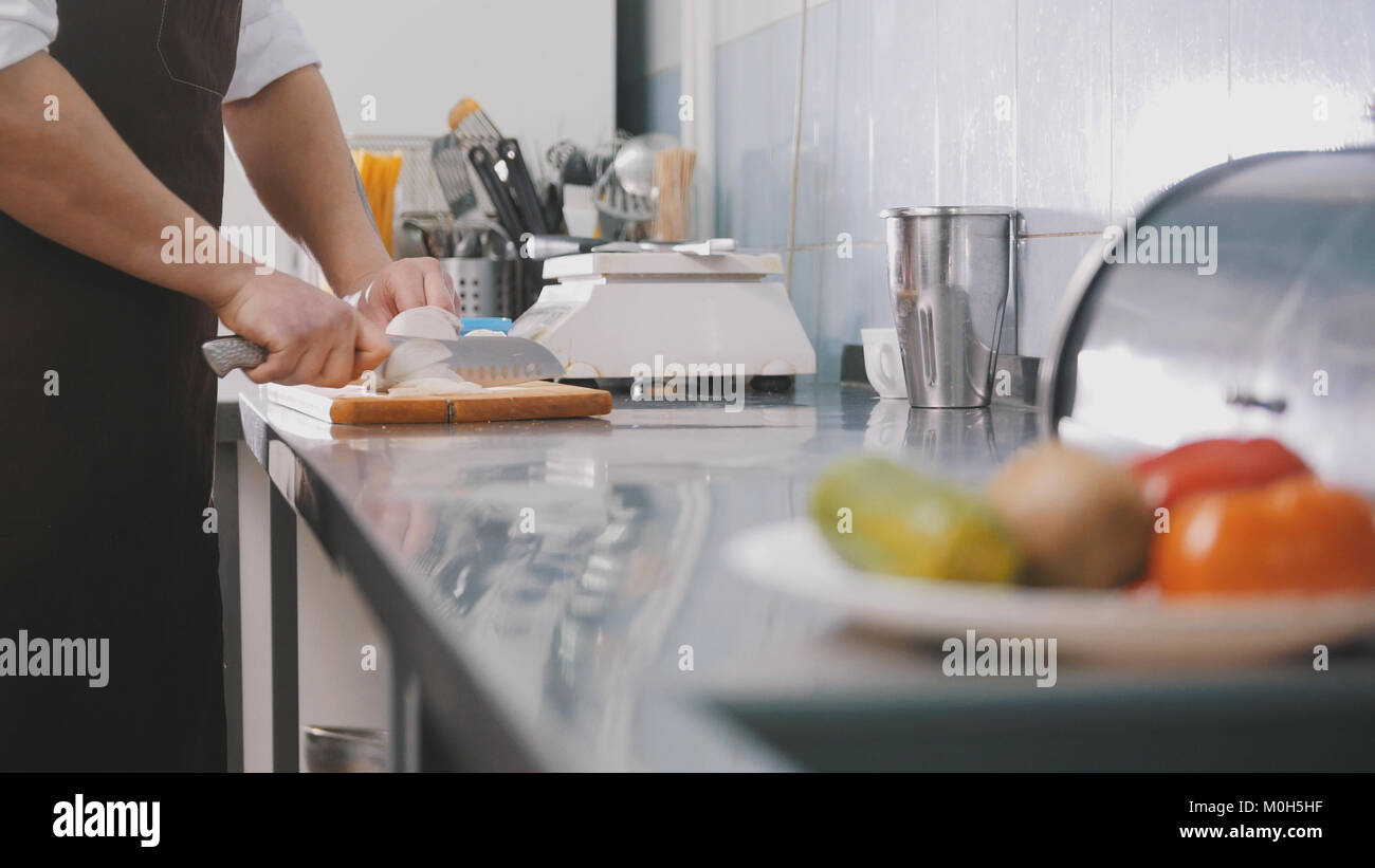 Male chef preparing salad in commercial kitchen - coupe l'oignon Banque D'Images