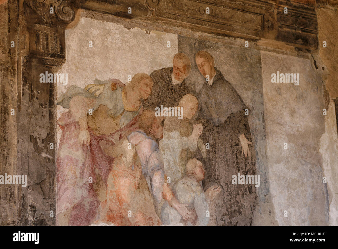 Belle fresque médiévale à l'intérieur d'un monastère de deux prêtres/moines avec les villageois priant à leurs pieds Banque D'Images