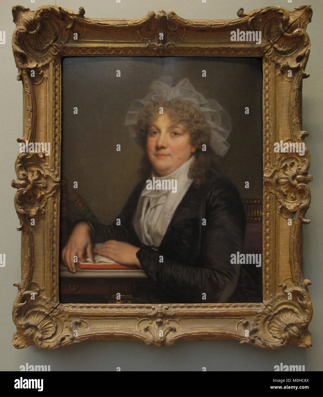 Ce portrait à l’huile sur bois de Jean‑Baptiste Greuze représente Anne Antoinette Desmoulins (1743-1817), épouse de l’acteur-manager Jean-Baptiste Nicolet, représentée à la fin des années 1780 avec des livres sur son bureau qui font référence à Molière et Rousseau, reflétant son rôle de directrice de théâtre après sa retraite en 1780. Le Metropolitan Museum of Art+1 Banque D'Images