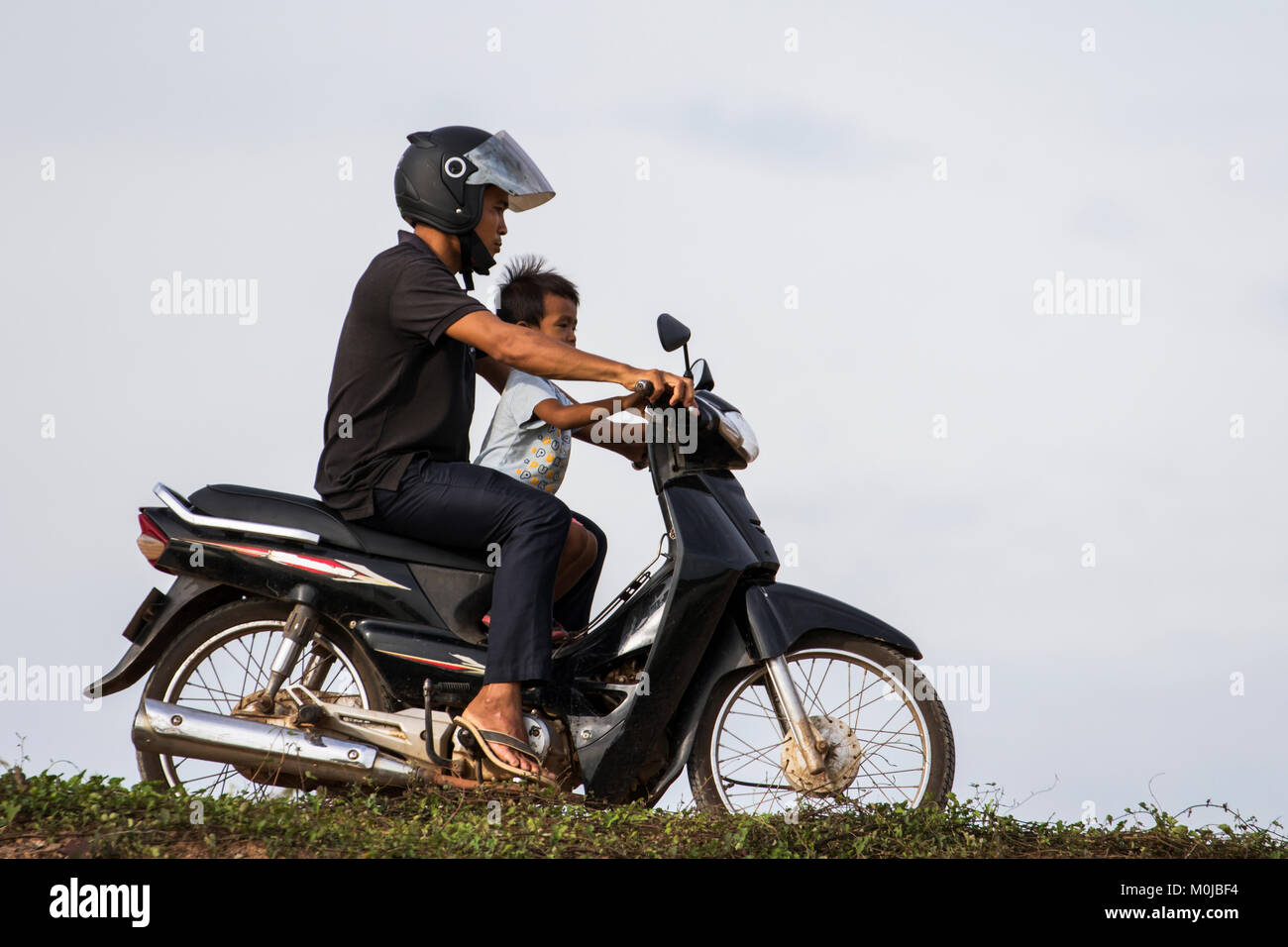 L'homme et le garçon sur une moto par le Tonle Sap, Siem Reap, Cambodge Banque D'Images